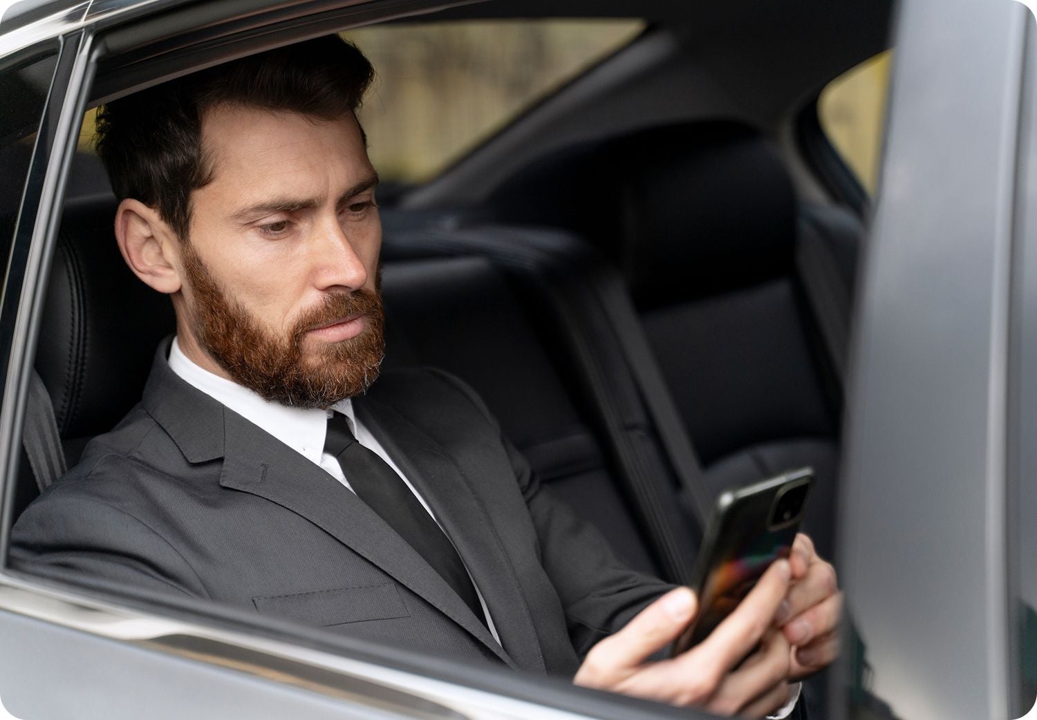 Exclusive customer looking at his phone in the back of a luxury car